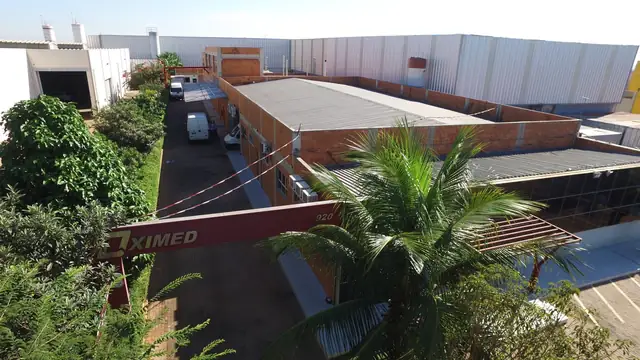 Vista aérea do portão da Oximed com o letreiro da empresa e os galpões