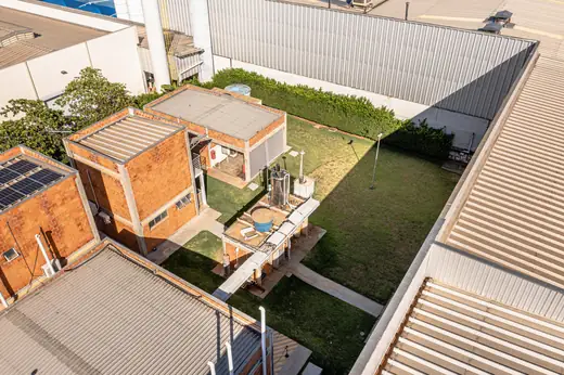 Vista aérea do pátio interno gramado da Oximed, entre os prédios de tijolos e galpões