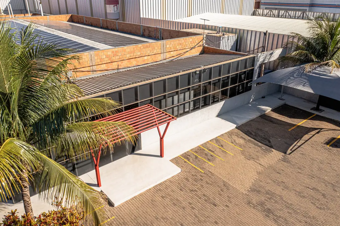 Fachada envidraçada da Oximed com a cobertura vermelha da entrada e coqueiros, vista de cima