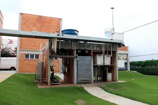 Instalação de tratamento ao ar livre, sob cobertura metálica, ao lado de prédio de tijolos da Oximed