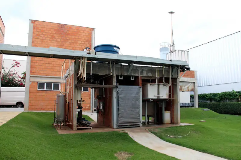 Instalação de tratamento ao ar livre, sob cobertura metálica, ao lado de prédio de tijolos da Oximed
