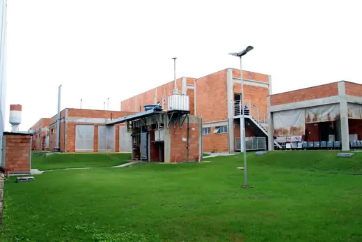 Gramado interno da Oximed com a instalação de tratamento e os prédios de tijolos ao fundo